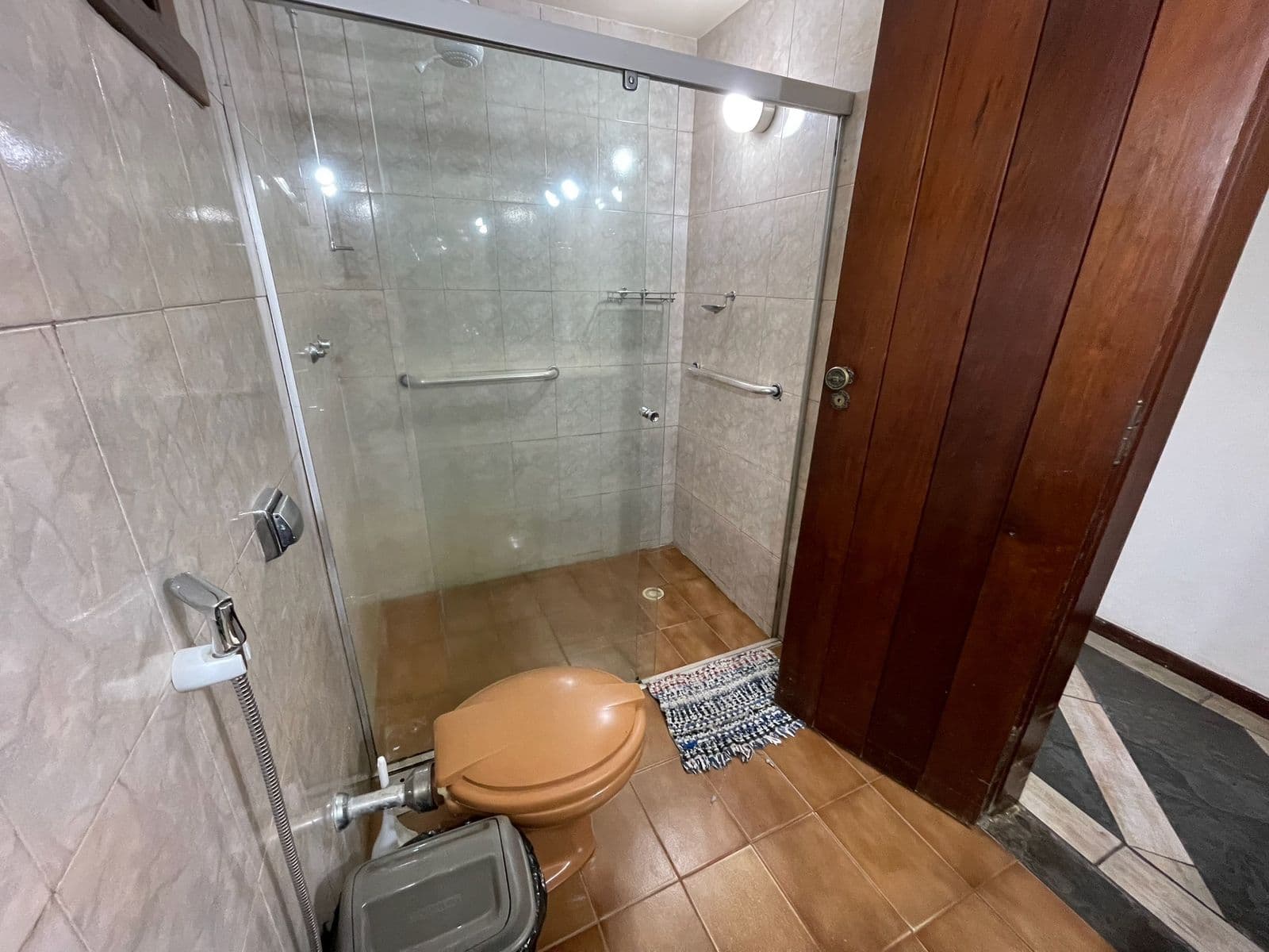Box de vidro do banheiro, com porta de madeira maciça ao lado