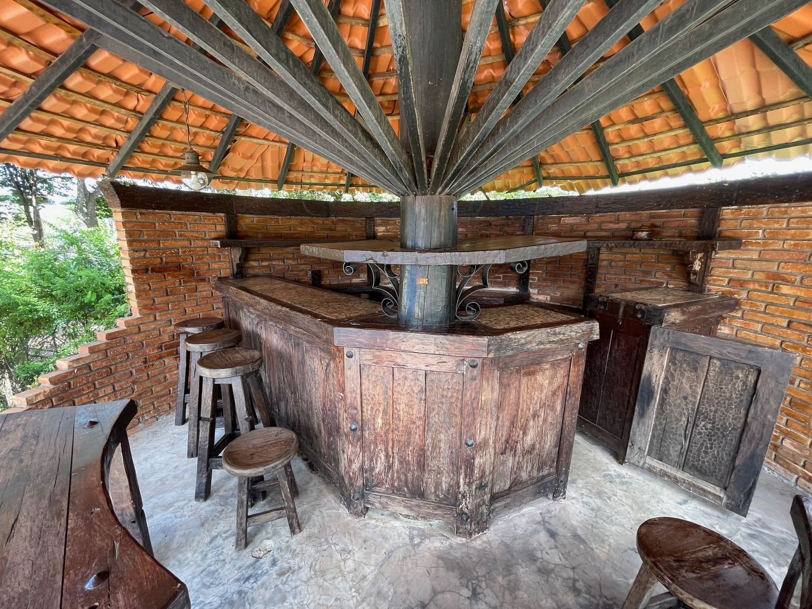 Balcão de bar em madeira maciça com banquetas altas, dentro do quiosque
