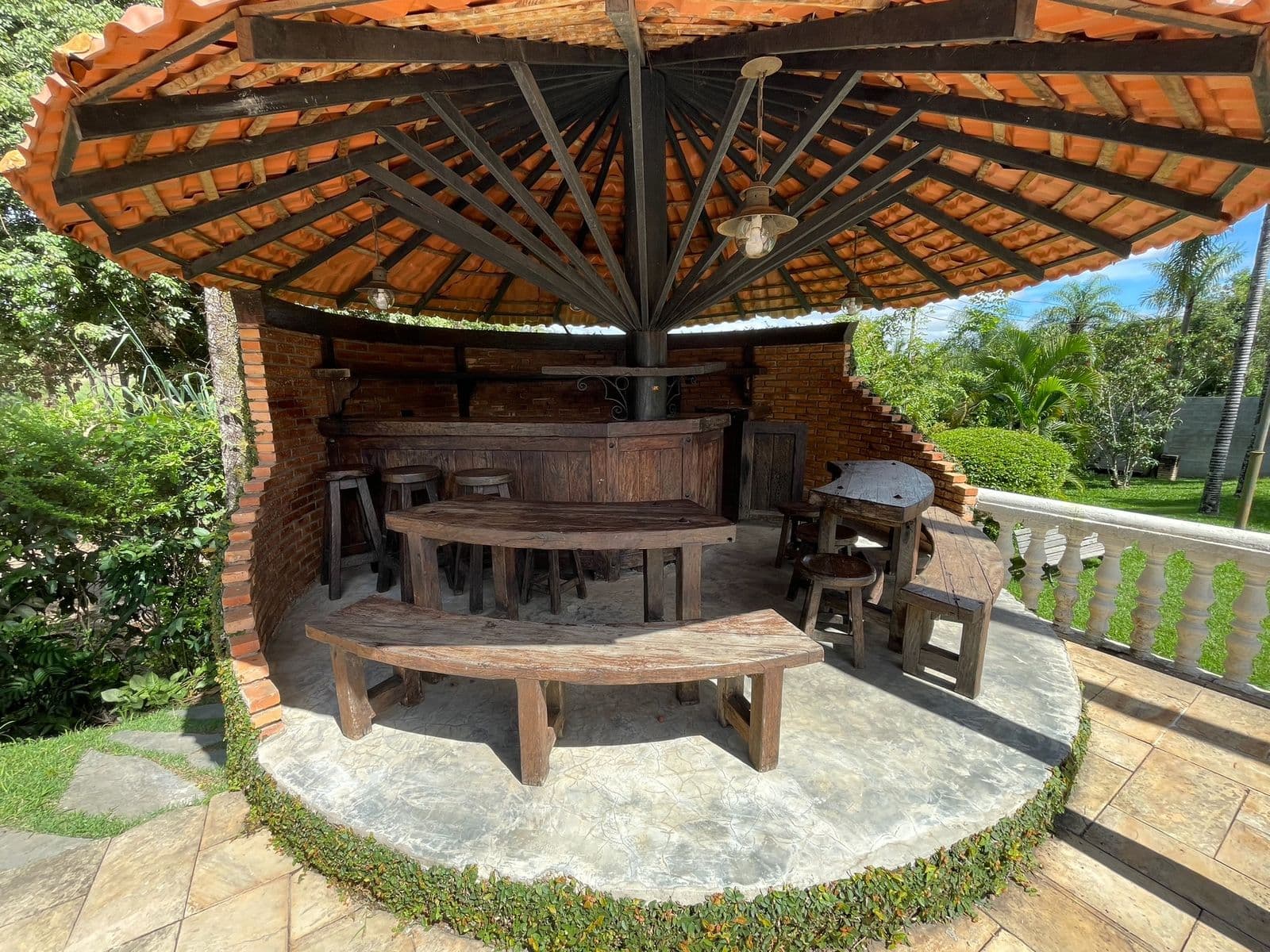 Quiosque redondo com balcão de bar, banquetas e bancos de madeira rústica