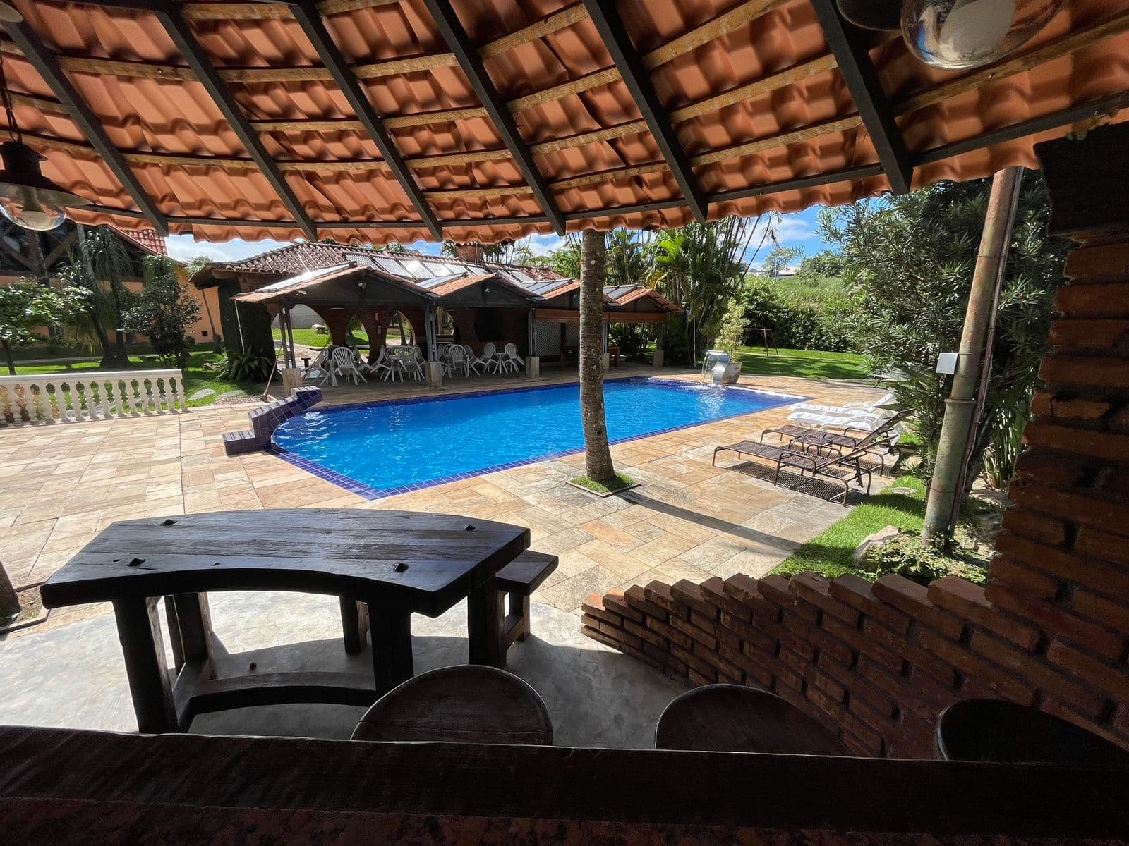 Vista de dentro do quiosque para a piscina e as espreguiçadeiras