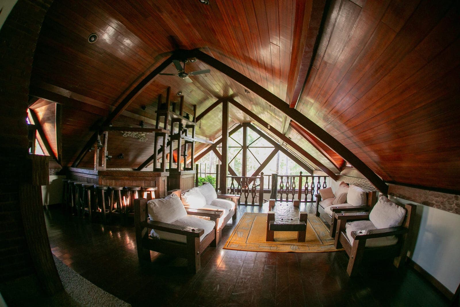 Sala de estar com pé-direito alto, teto de madeira e sofás claros