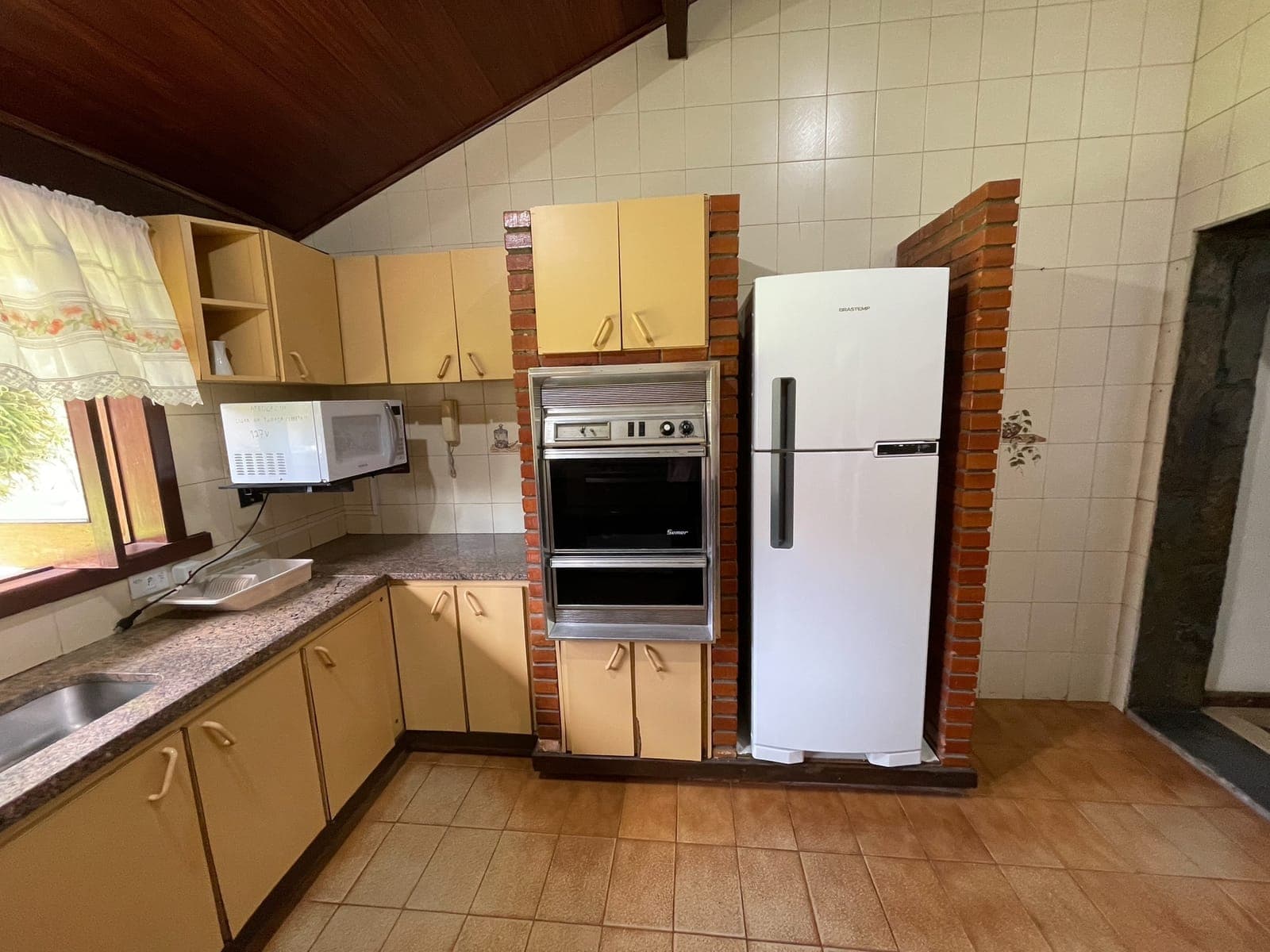 Cozinha equipada com fogão, geladeira, forno e armários amplos