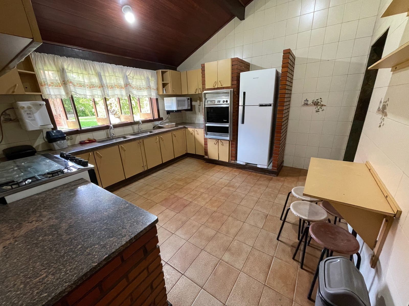 Cozinha com bancada de granito, ilha central e geladeira grande