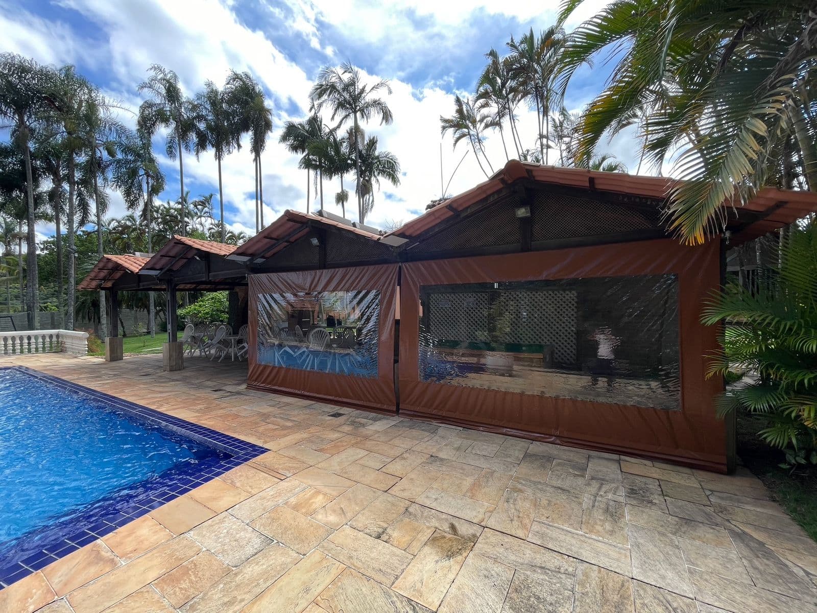 Fileira de quiosques cobertos de frente para a piscina, na sombra