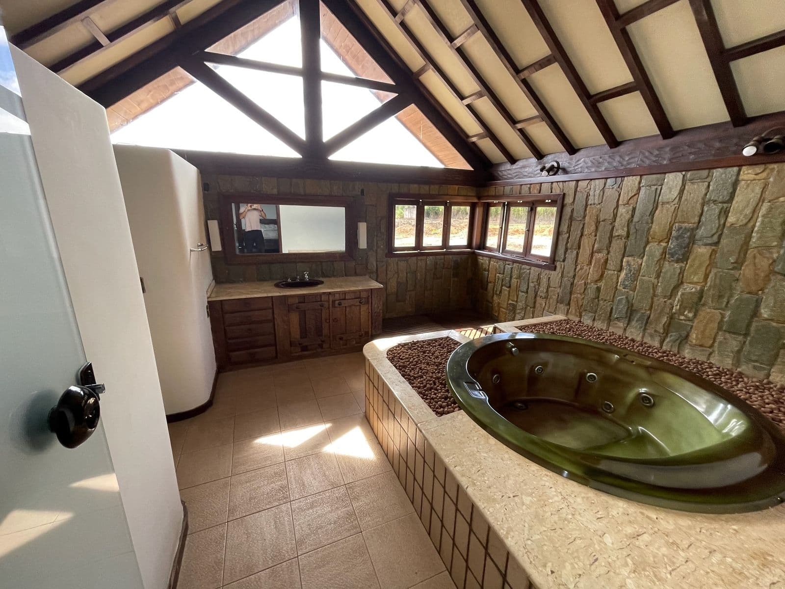 Hidromassagem da suíte vista de outro ângulo, com parede de pedra e bancada