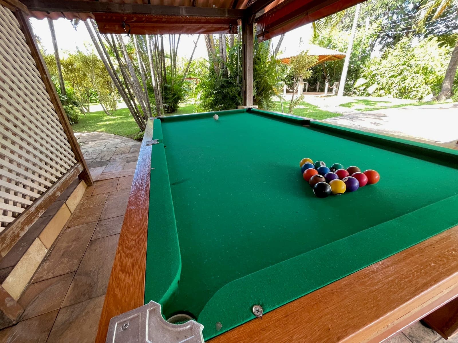 Mesa de sinuca em área coberta, ao lado da piscina