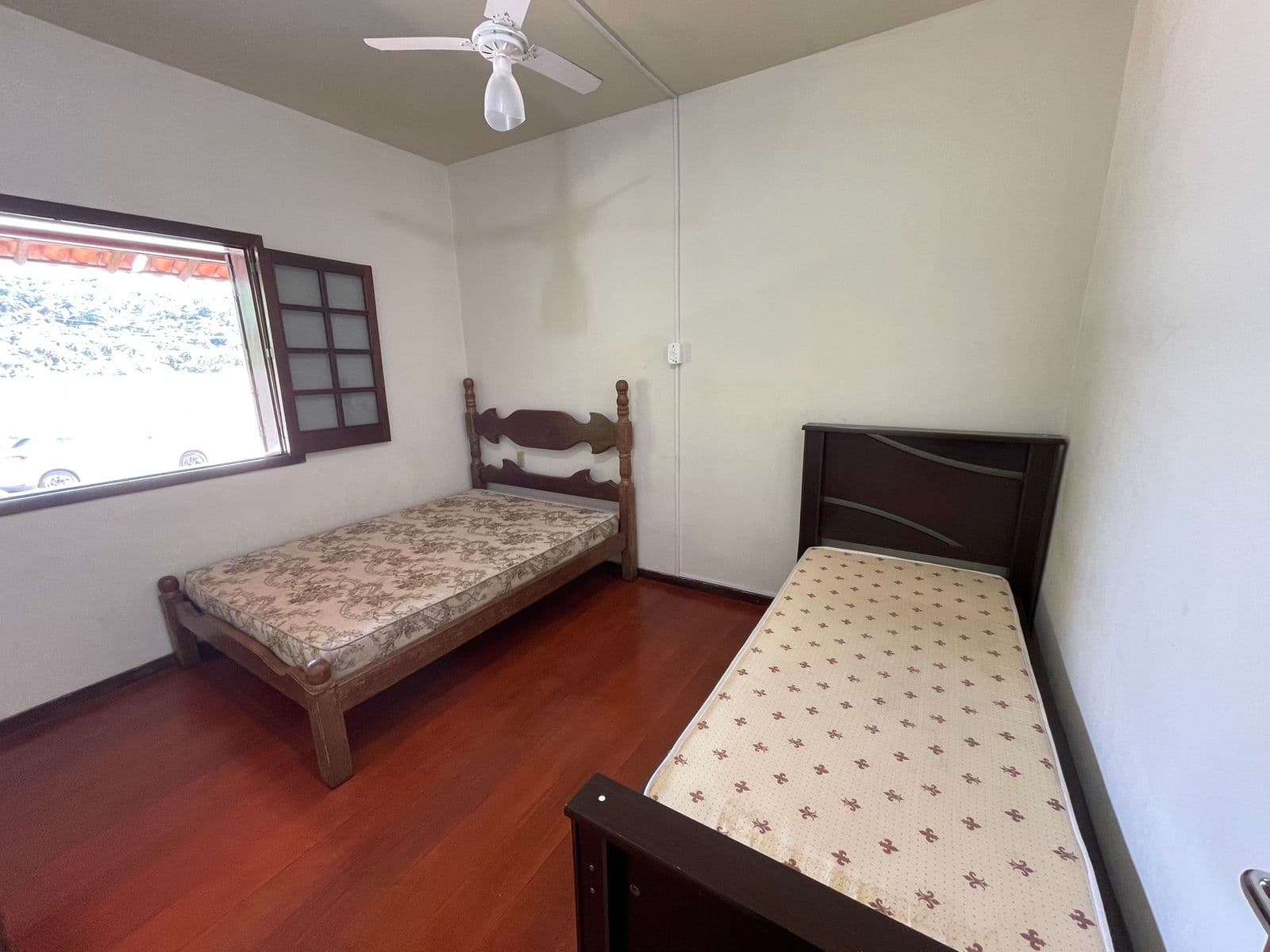 Quarto 5, com duas camas de solteiro e piso de madeira