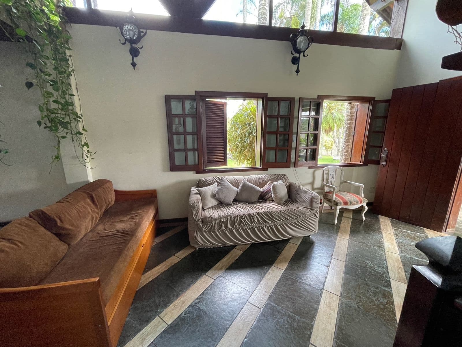 Sofás da sala de estar do primeiro andar, com janelas de madeira abertas para o jardim