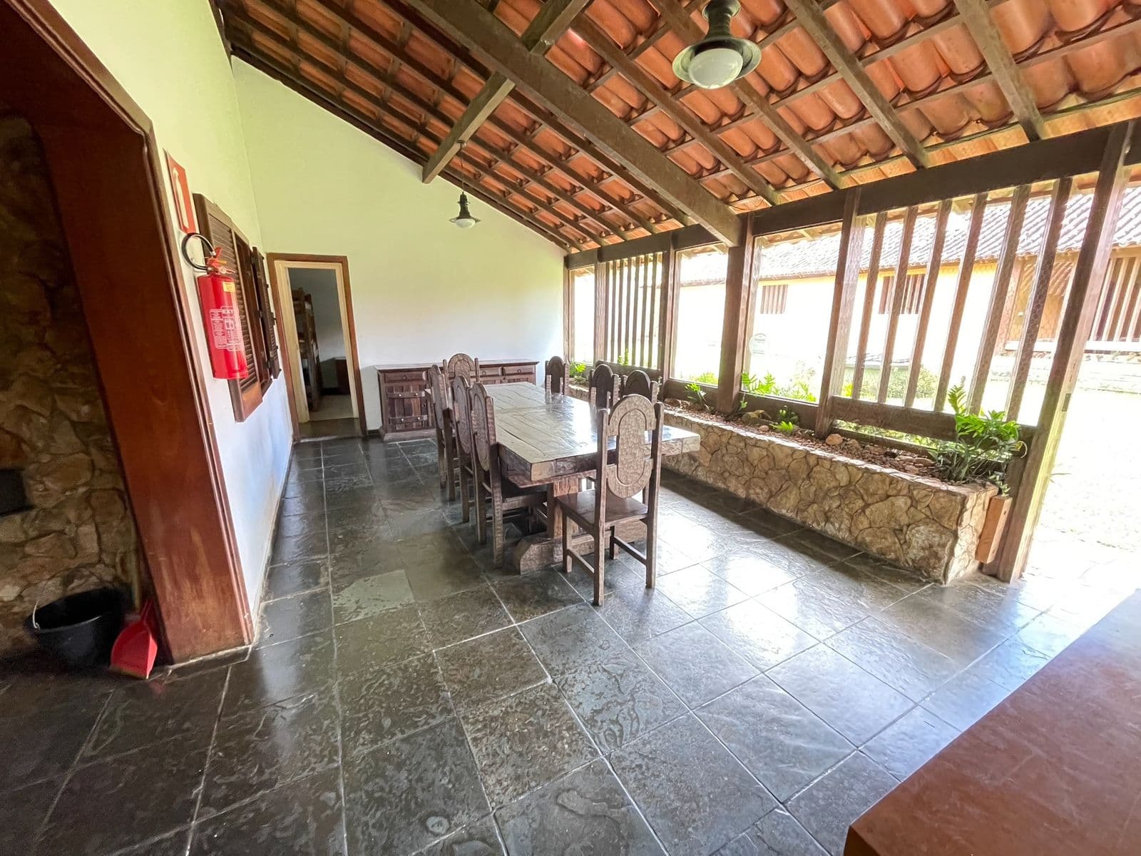 Sala de jantar coberta com telhado de telha aparente e cadeiras de madeira