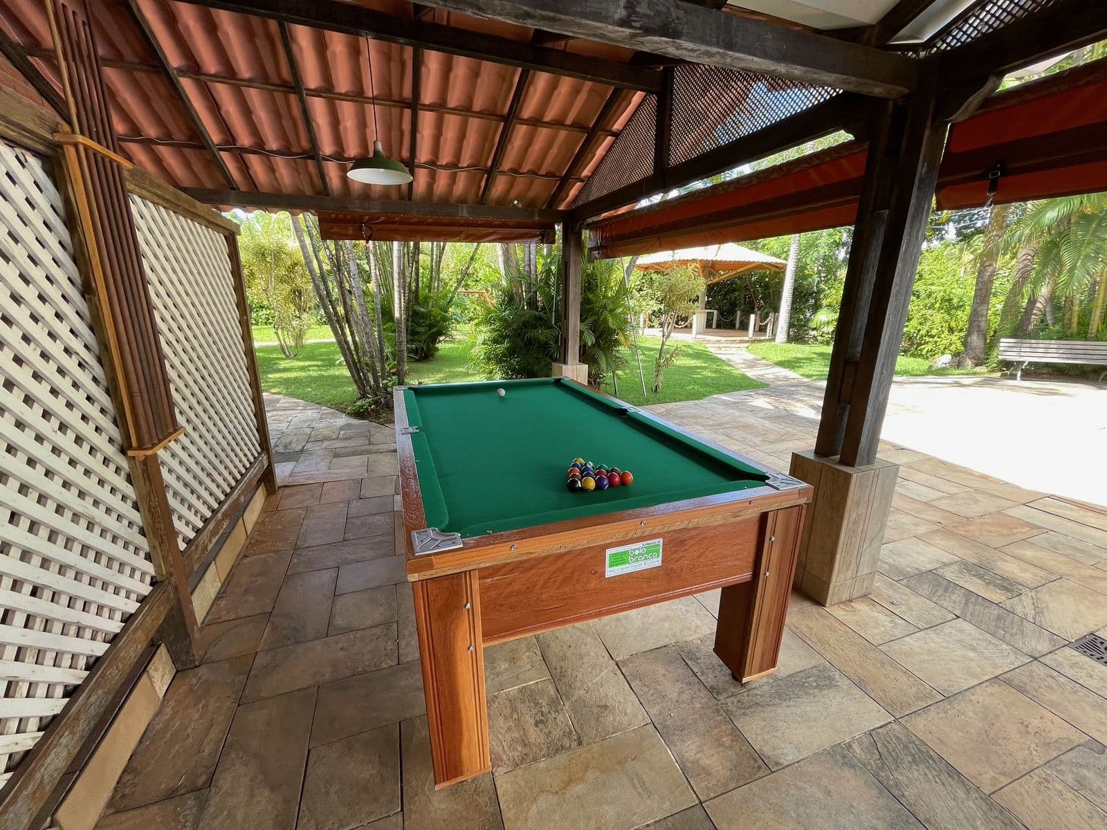 Mesa de sinuca em área coberta, aberta para o jardim